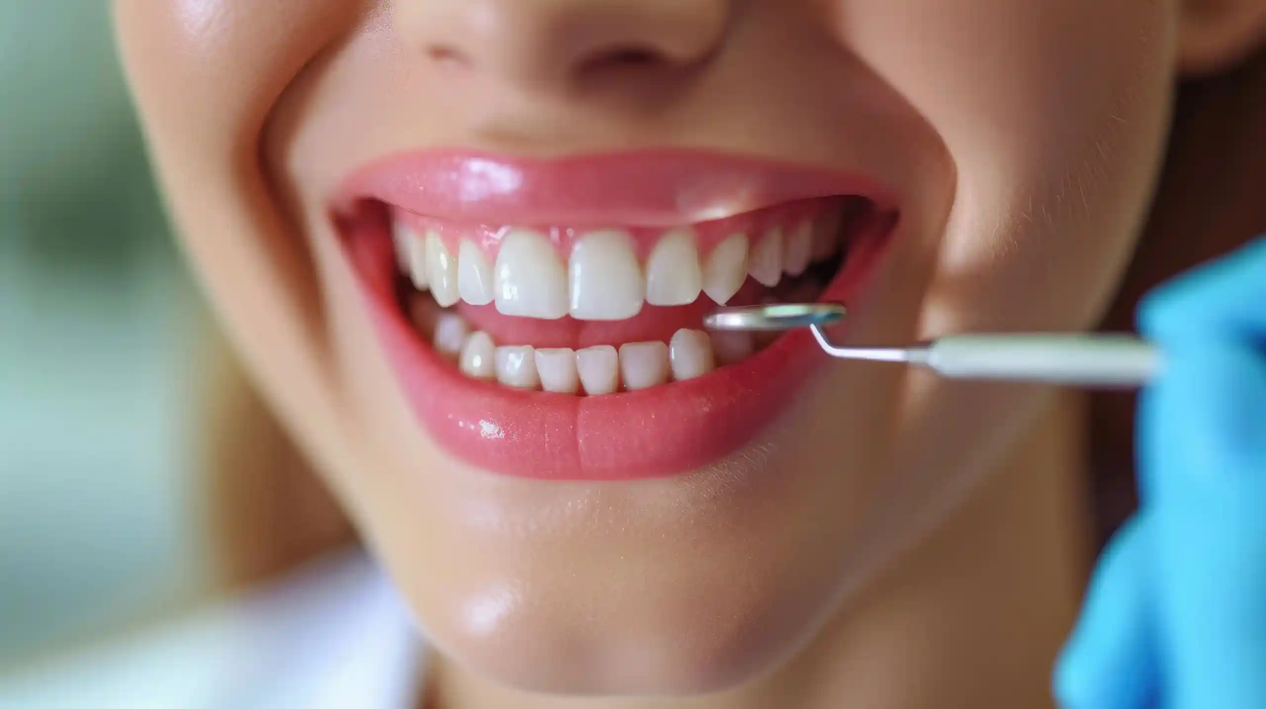 Gemini said A close-up of a person smiling with bright, even white teeth as a dentist uses a small dental mirror to examine them.